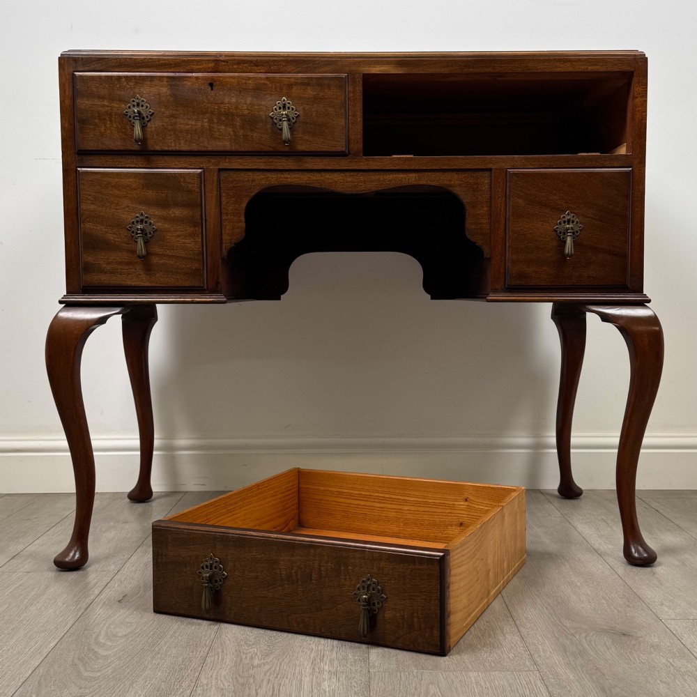 An Edwardian mahogany writing table featuring four drawers with ornamental brass drop handles, a central kneehole aperture, and four cabriole legs. View X