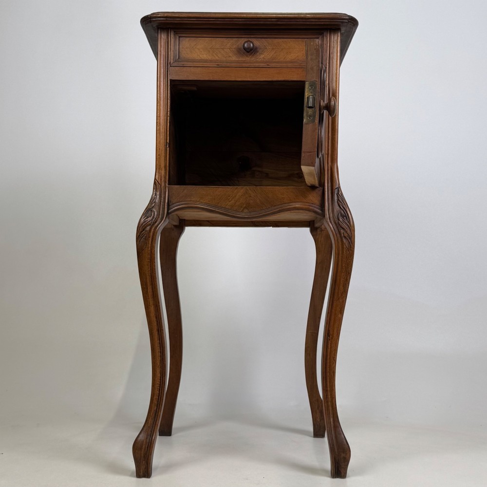 An antique French walnut bedside cabinet featuring high slender cabriole legs, a single drawer, and a carved wooden door with a marquetry panel. View II