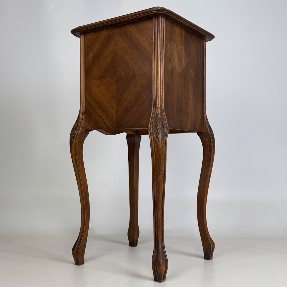 An antique French walnut bedside cabinet featuring high slender cabriole legs, a single drawer, and a carved wooden door with a marquetry panel. View V
