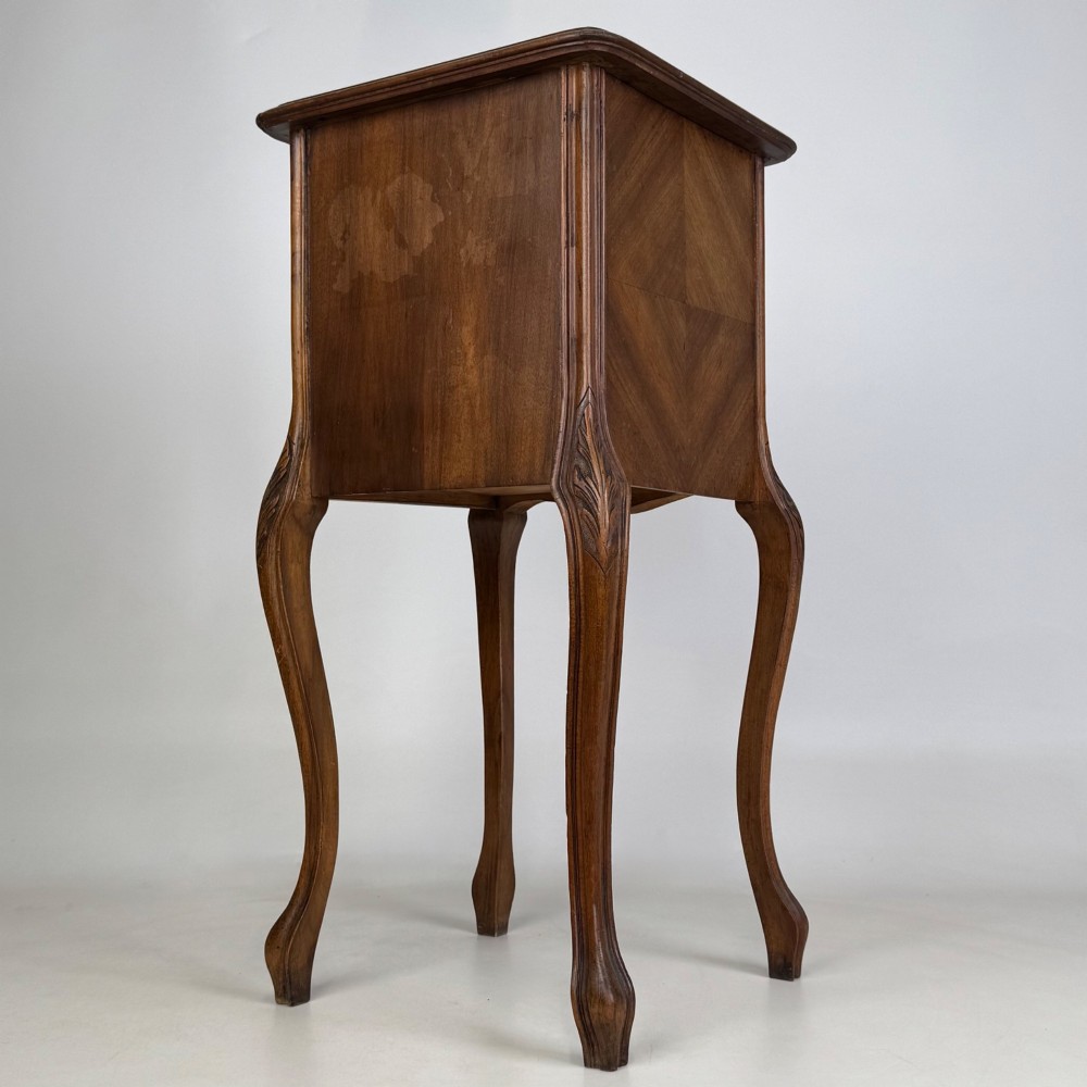 An antique French walnut bedside cabinet featuring high slender cabriole legs, a single drawer, and a carved wooden door with a marquetry panel. View VII