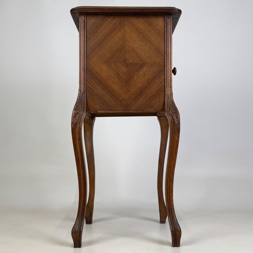 An antique French walnut bedside cabinet featuring high slender cabriole legs, a single drawer, and a carved wooden door with a marquetry panel. View VIII