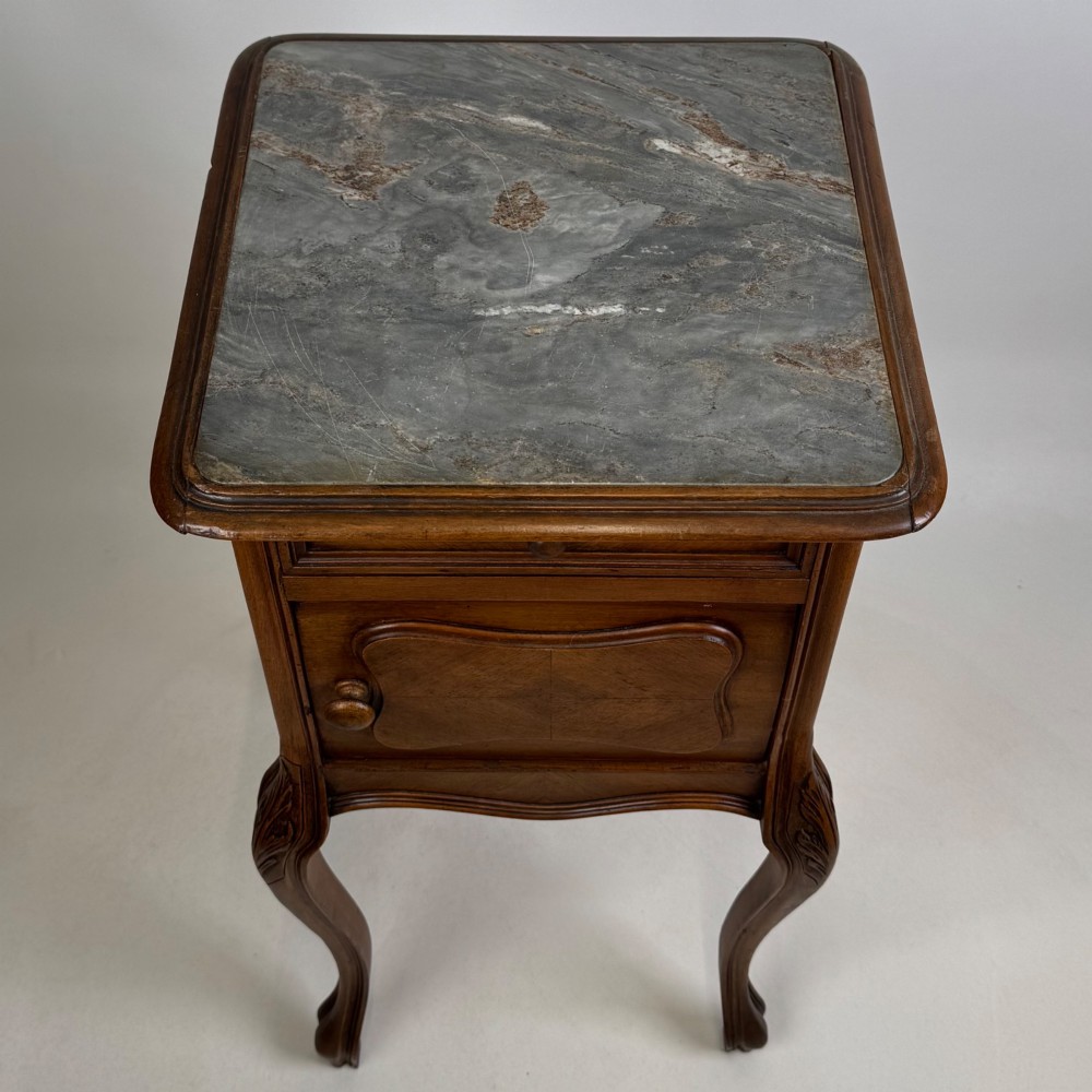 An antique French walnut bedside cabinet featuring high slender cabriole legs, a single drawer, and a carved wooden door with a marquetry panel. View X