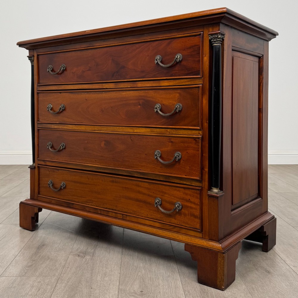 A 20th-century Georgian style mahogany chest featuring four full-width drawers with brass drop handles, flanked by ebonised side columns, resting on bracket feet. View II