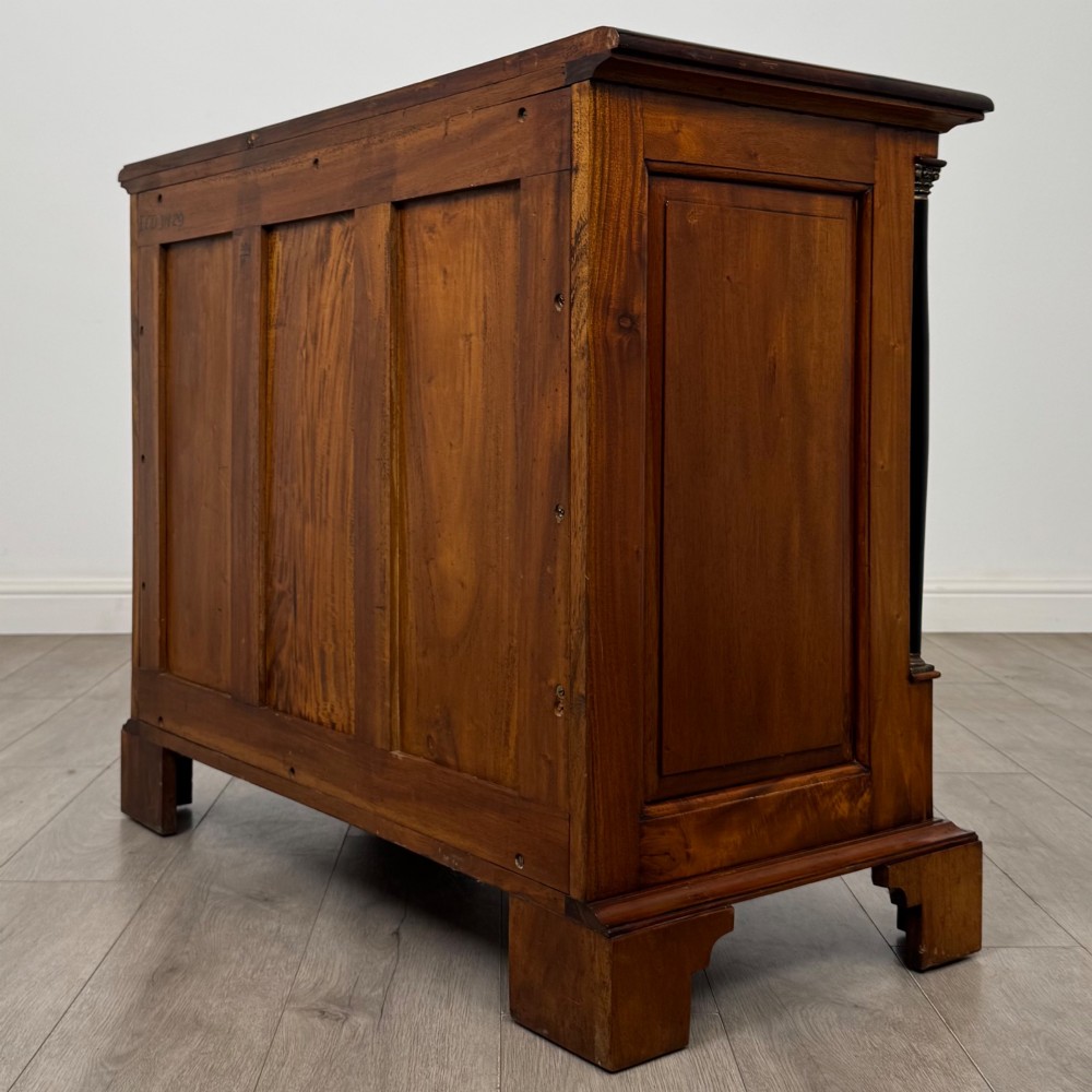 A 20th-century Georgian style mahogany chest featuring four full-width drawers with brass drop handles, flanked by ebonised side columns, resting on bracket feet. View VI