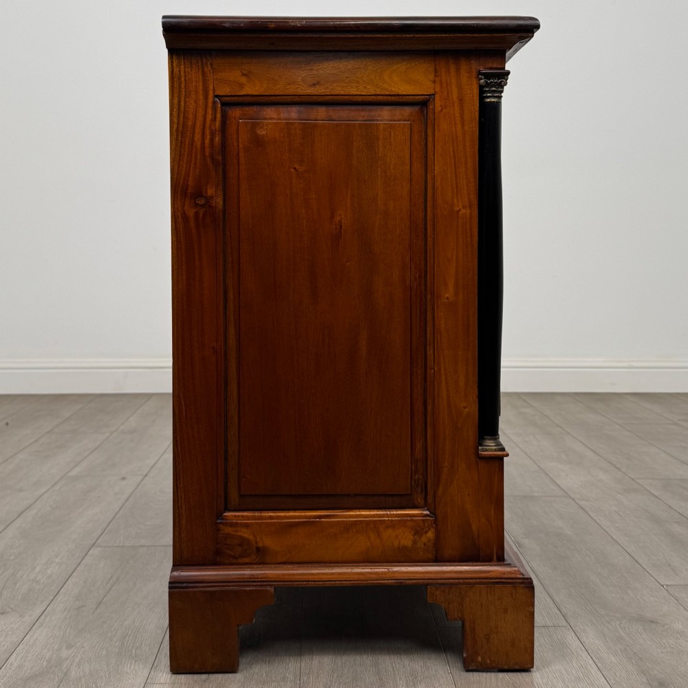 A 20th-century Georgian style mahogany chest featuring four full-width drawers with brass drop handles, flanked by ebonised side columns, resting on bracket feet. View VII