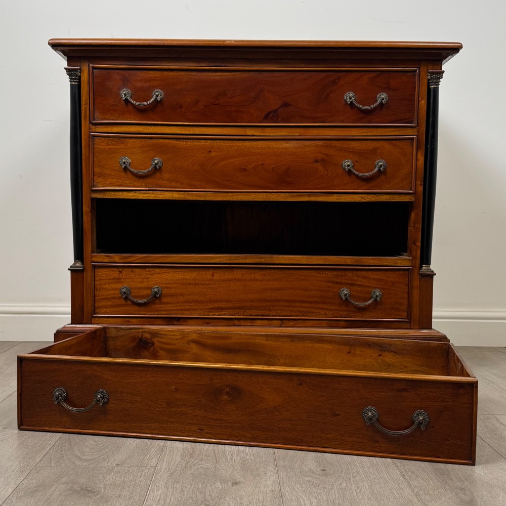 A 20th-century Georgian style mahogany chest featuring four full-width drawers with brass drop handles, flanked by ebonised side columns, resting on bracket feet. View X