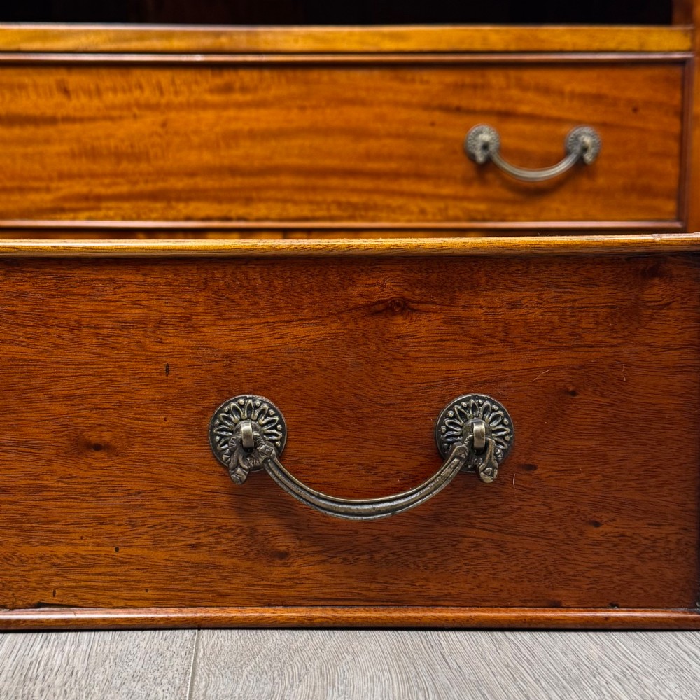 A 20th-century Georgian style mahogany chest featuring four full-width drawers with brass drop handles, flanked by ebonised side columns, resting on bracket feet. View XI