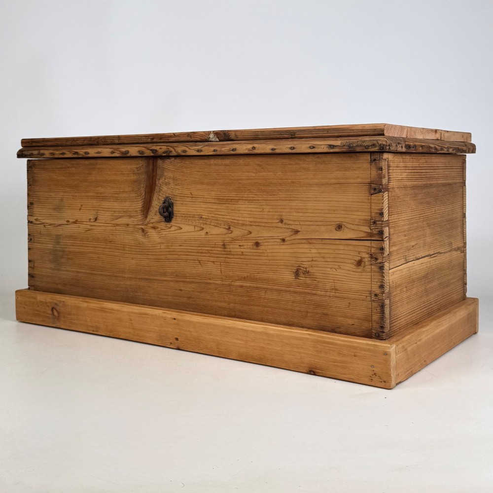 A nineteenth-century Victorian pine blanket box featuring a flat hinged lid, central iron keyhole escutcheon, visible corner joinery, and a solid plinth base. View II