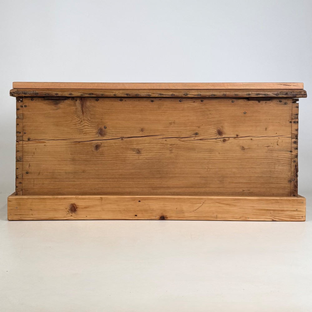 A nineteenth-century Victorian pine blanket box featuring a flat hinged lid, central iron keyhole escutcheon, visible corner joinery, and a solid plinth base. View V