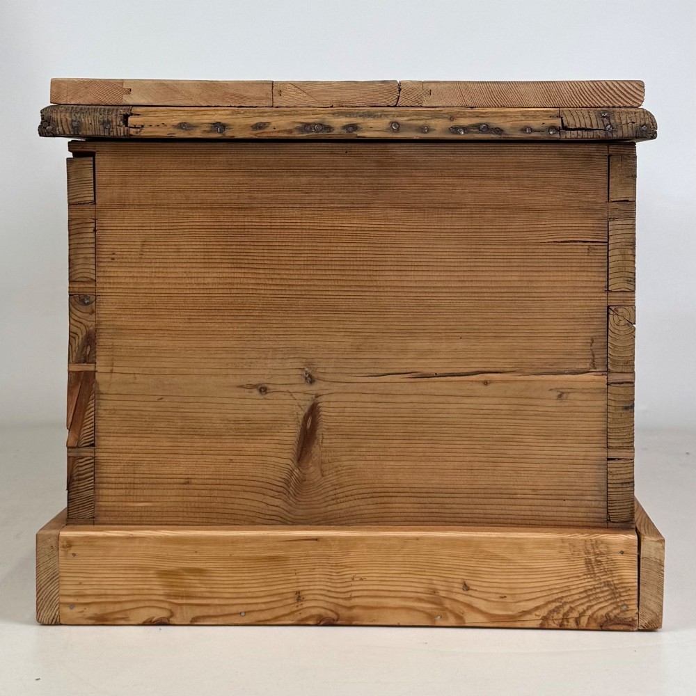 A nineteenth-century Victorian pine blanket box featuring a flat hinged lid, central iron keyhole escutcheon, visible corner joinery, and a solid plinth base. View VII