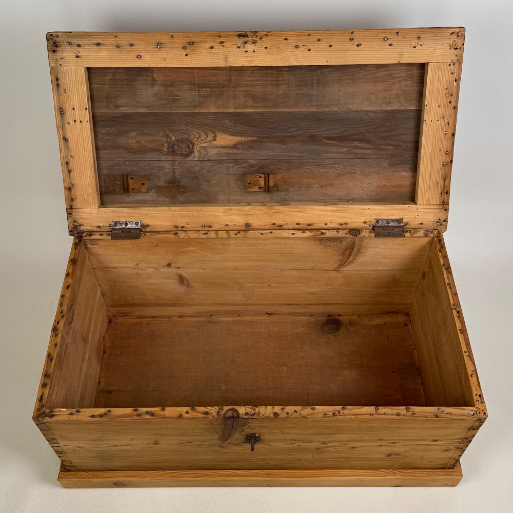 A nineteenth-century Victorian pine blanket box featuring a flat hinged lid, central iron keyhole escutcheon, visible corner joinery, and a solid plinth base. View X