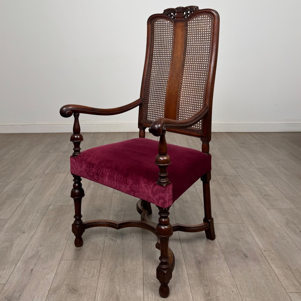 A set of mahogany dining chairs featuring high cane-panelled backs, carved top crests, turned legs, and deep red velvet seats. View II