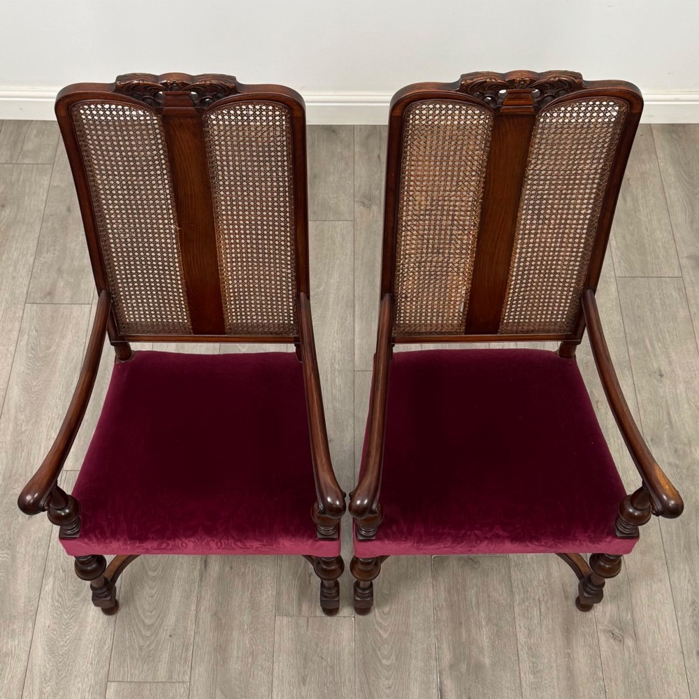 A set of mahogany dining chairs featuring high cane-panelled backs, carved top crests, turned legs, and deep red velvet seats. View VIII