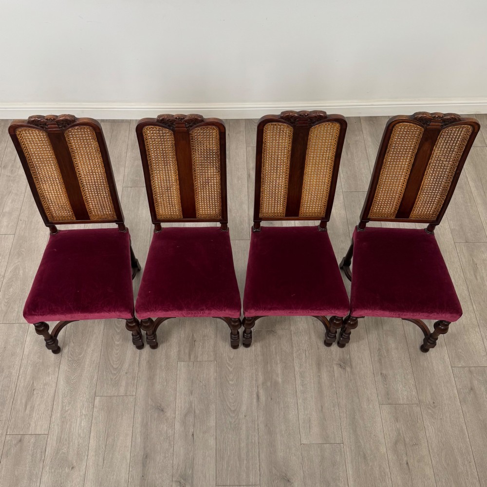 A set of mahogany dining chairs featuring high cane-panelled backs, carved top crests, turned legs, and deep red velvet seats. View IX