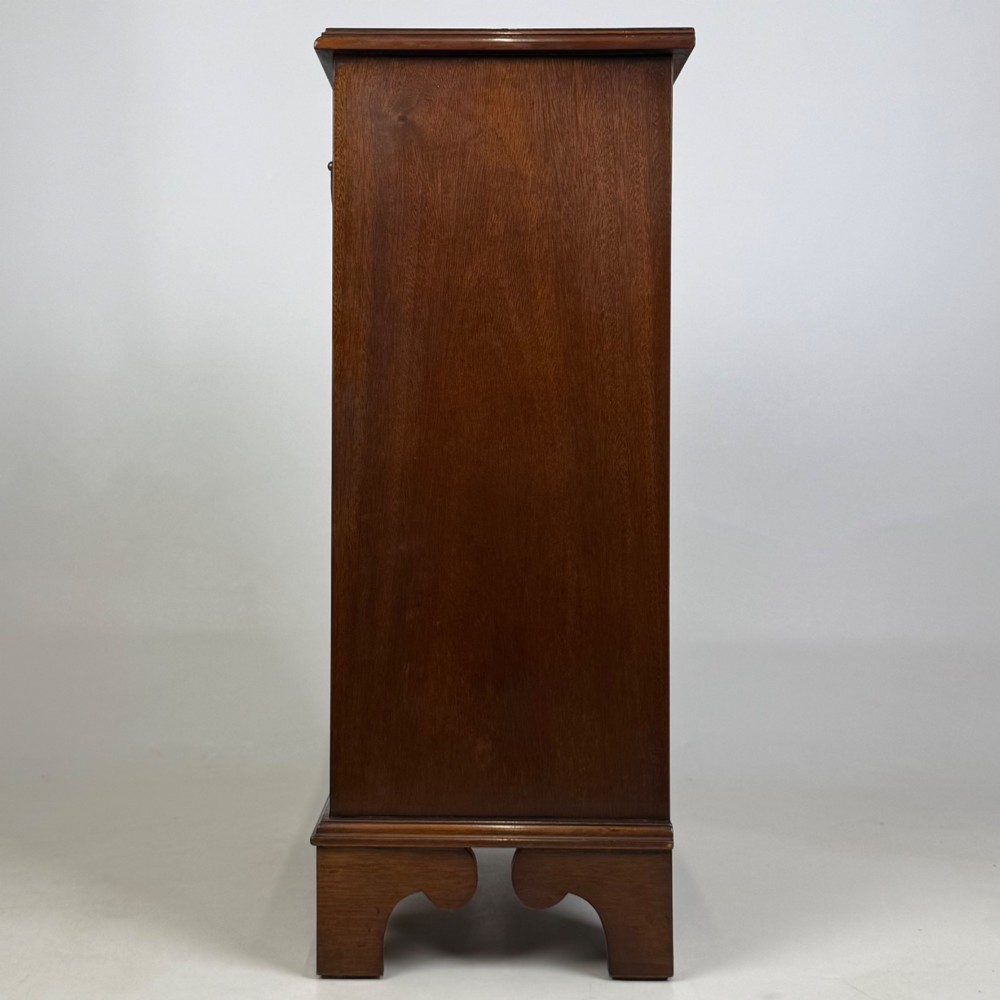 A small mahogany open bookcase featuring a single top drawer with brass swan-neck handles, satinwood inlay, open lower shelving, and shaped bracket feet. View III