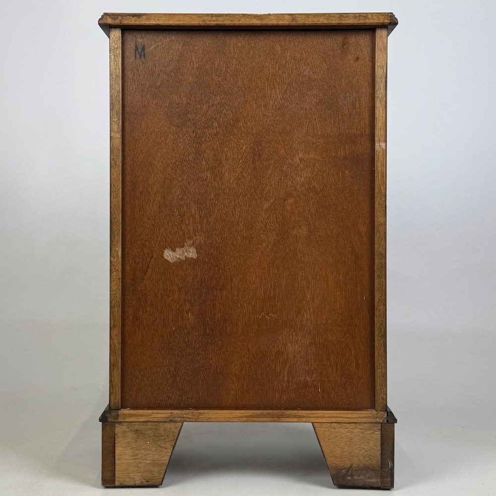A small mahogany open bookcase featuring a single top drawer with brass swan-neck handles, satinwood inlay, open lower shelving, and shaped bracket feet. View V