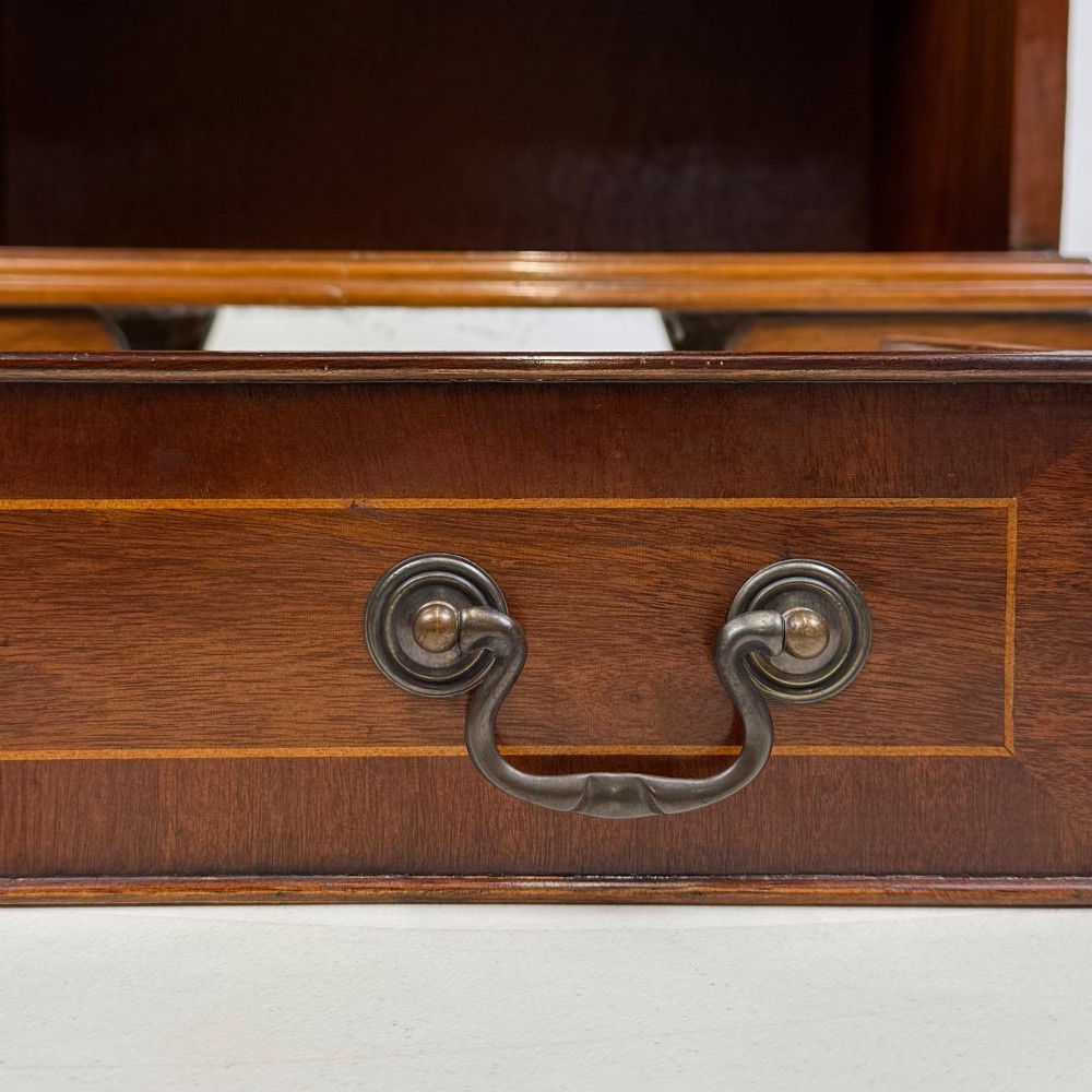 A small mahogany open bookcase featuring a single top drawer with brass swan-neck handles, satinwood inlay, open lower shelving, and shaped bracket feet. View X