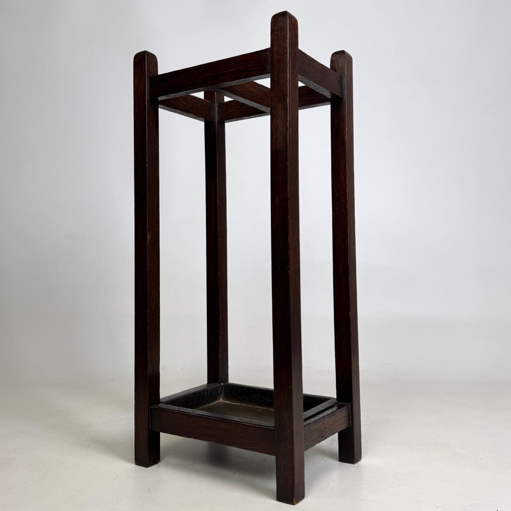 A small dark oak Edwardian umbrella stand featuring a square wooden frame with an upper section divider and a metal drip tray at the base. View II