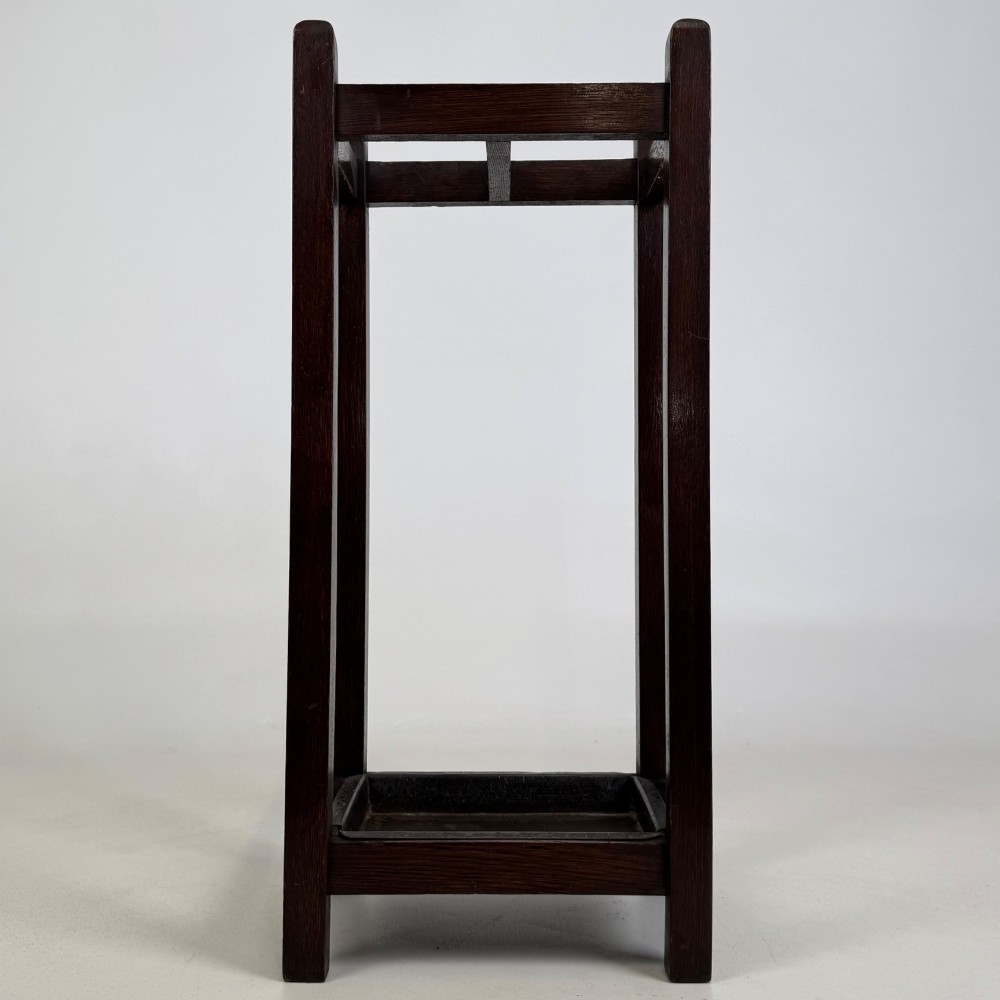 A small dark oak Edwardian umbrella stand featuring a square wooden frame with an upper section divider and a metal drip tray at the base. View V