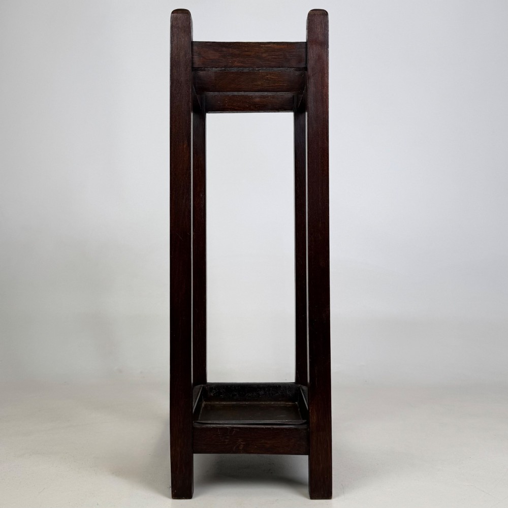A small dark oak Edwardian umbrella stand featuring a square wooden frame with an upper section divider and a metal drip tray at the base. View VII