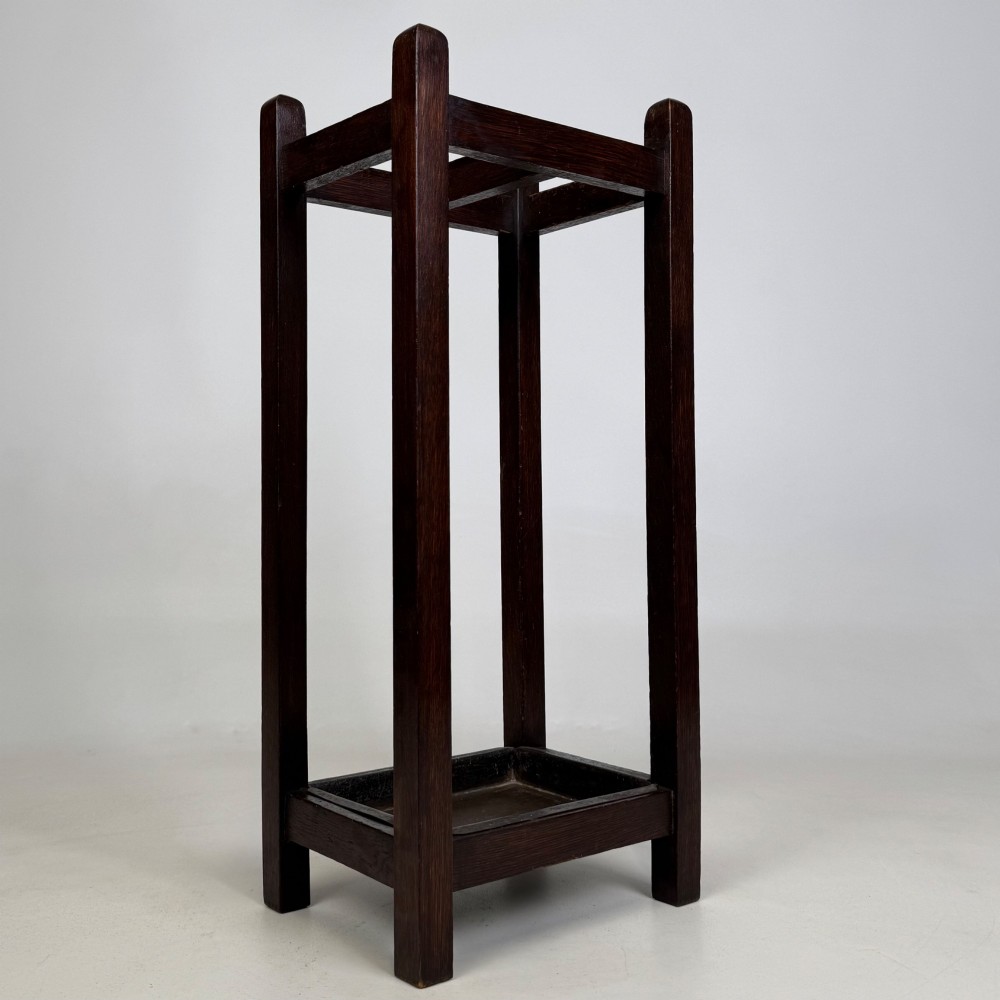 A small dark oak Edwardian umbrella stand featuring a square wooden frame with an upper section divider and a metal drip tray at the base. View VIII