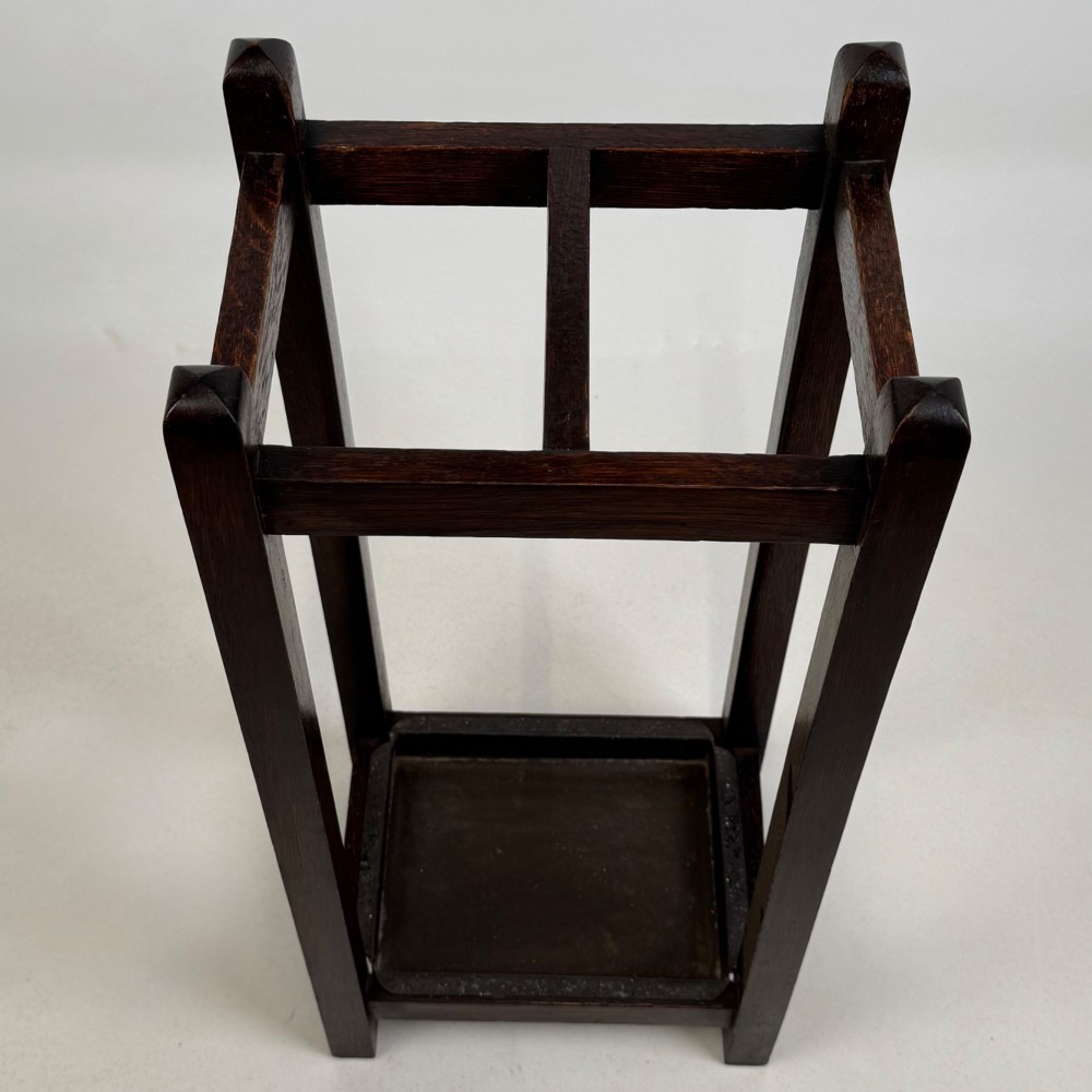 A small dark oak Edwardian umbrella stand featuring a square wooden frame with an upper section divider and a metal drip tray at the base. View IX