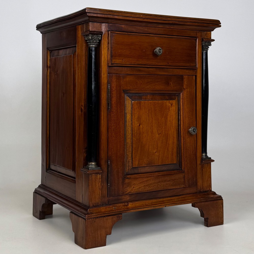 A pair of matching mahogany bedside cabinets with single top drawers, panelled cupboard doors, and black ebonised side columns. View X
