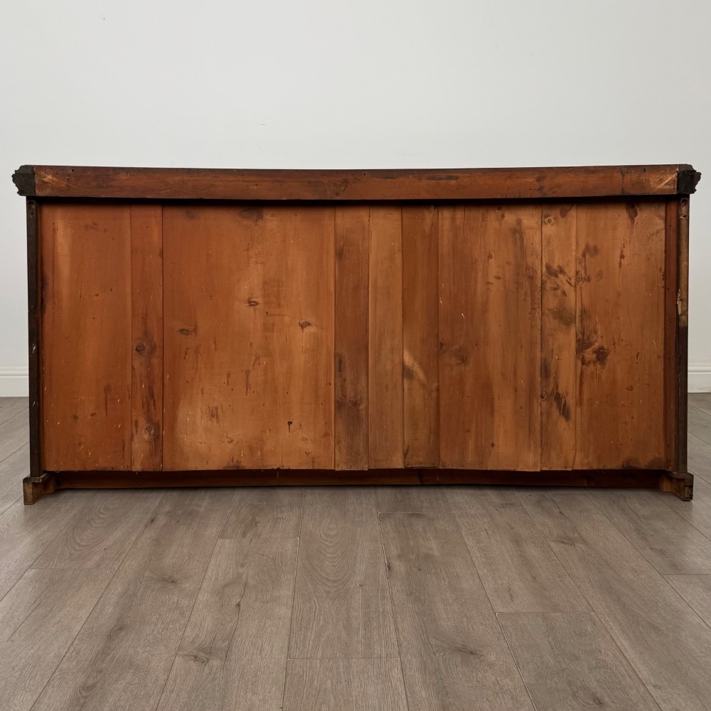 A wide 19th-century Victorian dark oak sideboard featuring relief-carved floral panels, central drawers with brass handles, and lower cupboard doors. View VI