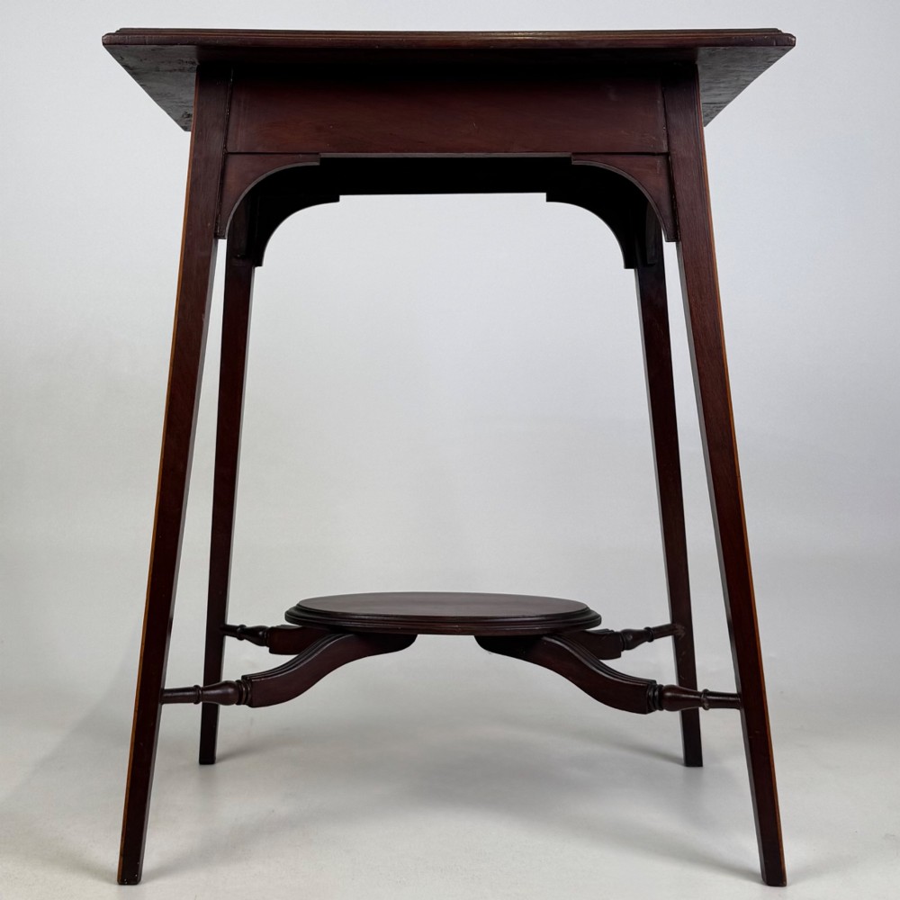 An Edwardian mahogany side table featuring a square top, splayed legs, corner spandrels, and a central circular undertier supported by shaped stretchers.