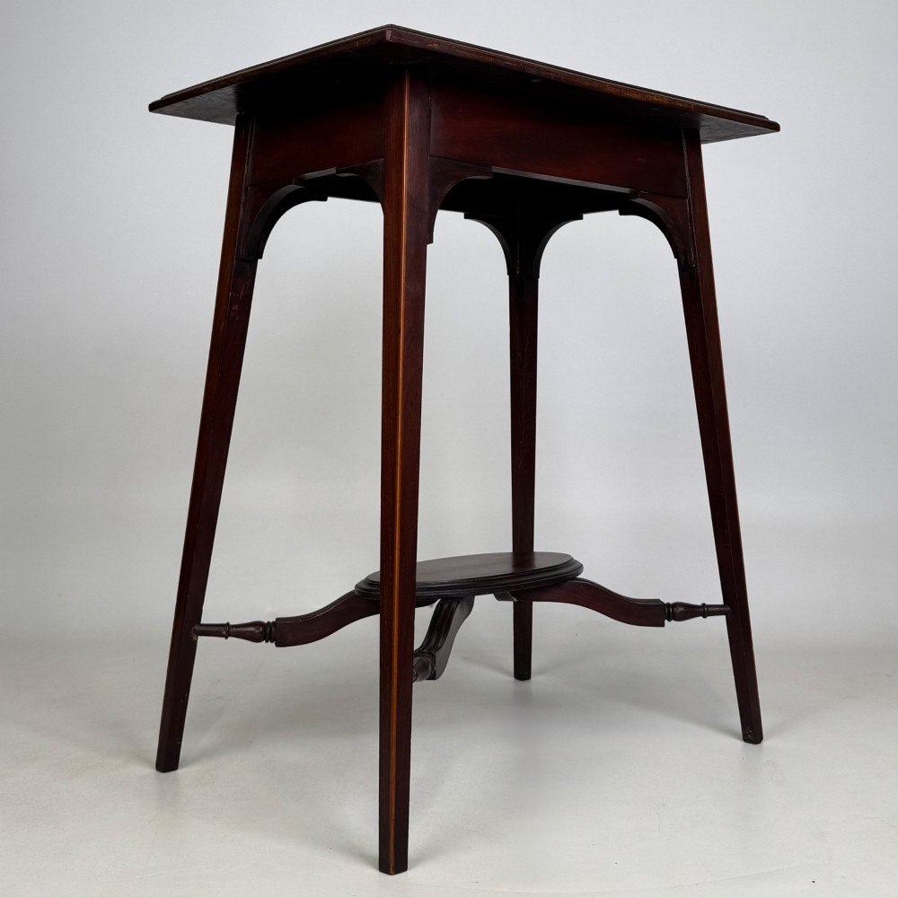 An Edwardian mahogany side table featuring a square top, splayed legs, corner spandrels, and a central circular undertier supported by shaped stretchers. View IV