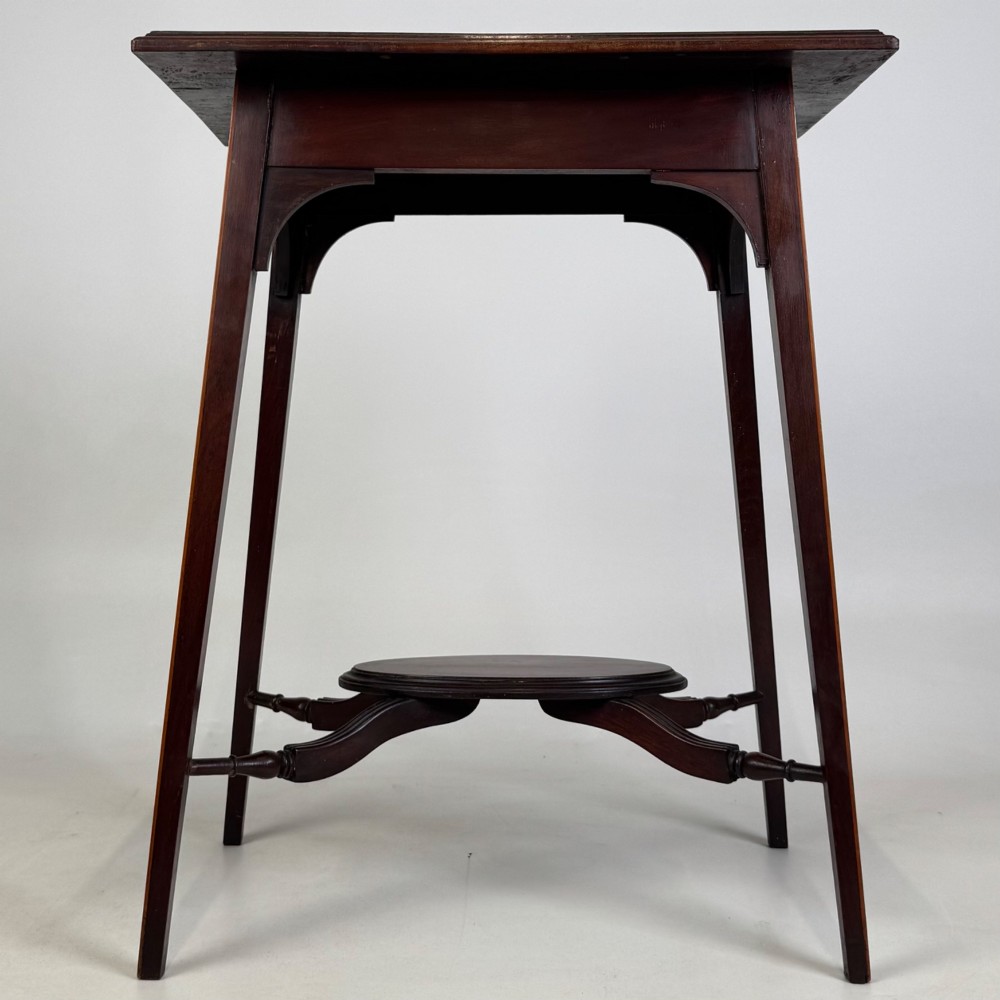 An Edwardian mahogany side table featuring a square top, splayed legs, corner spandrels, and a central circular undertier supported by shaped stretchers. View V