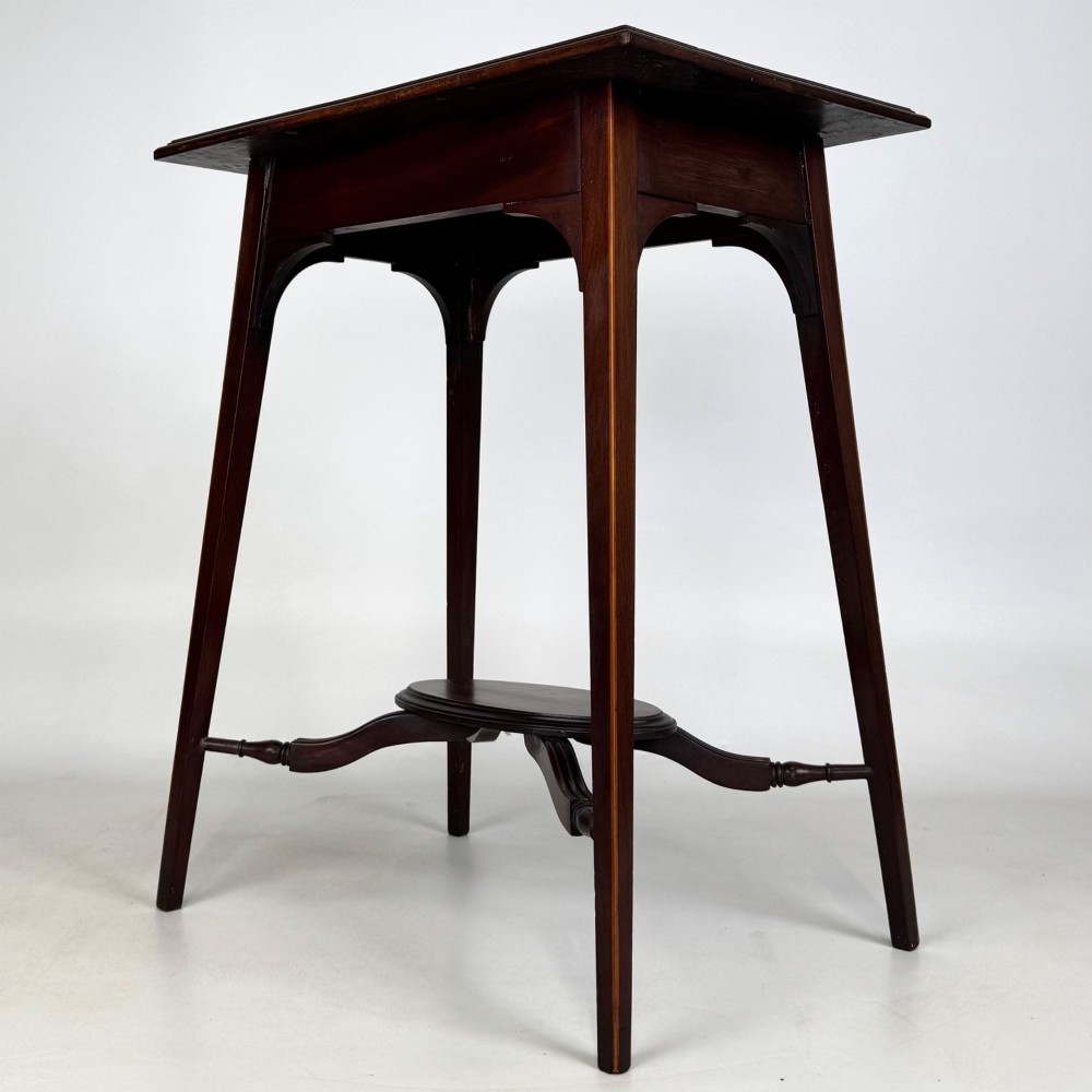 An Edwardian mahogany side table featuring a square top, splayed legs, corner spandrels, and a central circular undertier supported by shaped stretchers. View VI