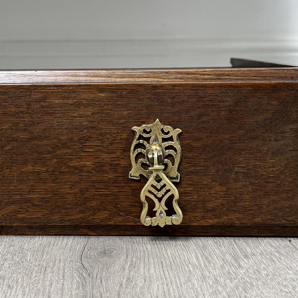 An Edwardian dark oak sideboard featuring a shaped upstand gallery, two top drawers with brass drop handles, twin raised-panel cupboard doors, and front barley twist legs. View XII