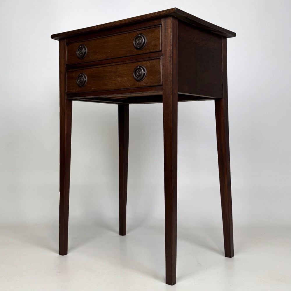 An antique dark mahogany side table featuring two stacked drawers with circular handles, supported by tall tapered square legs. View II