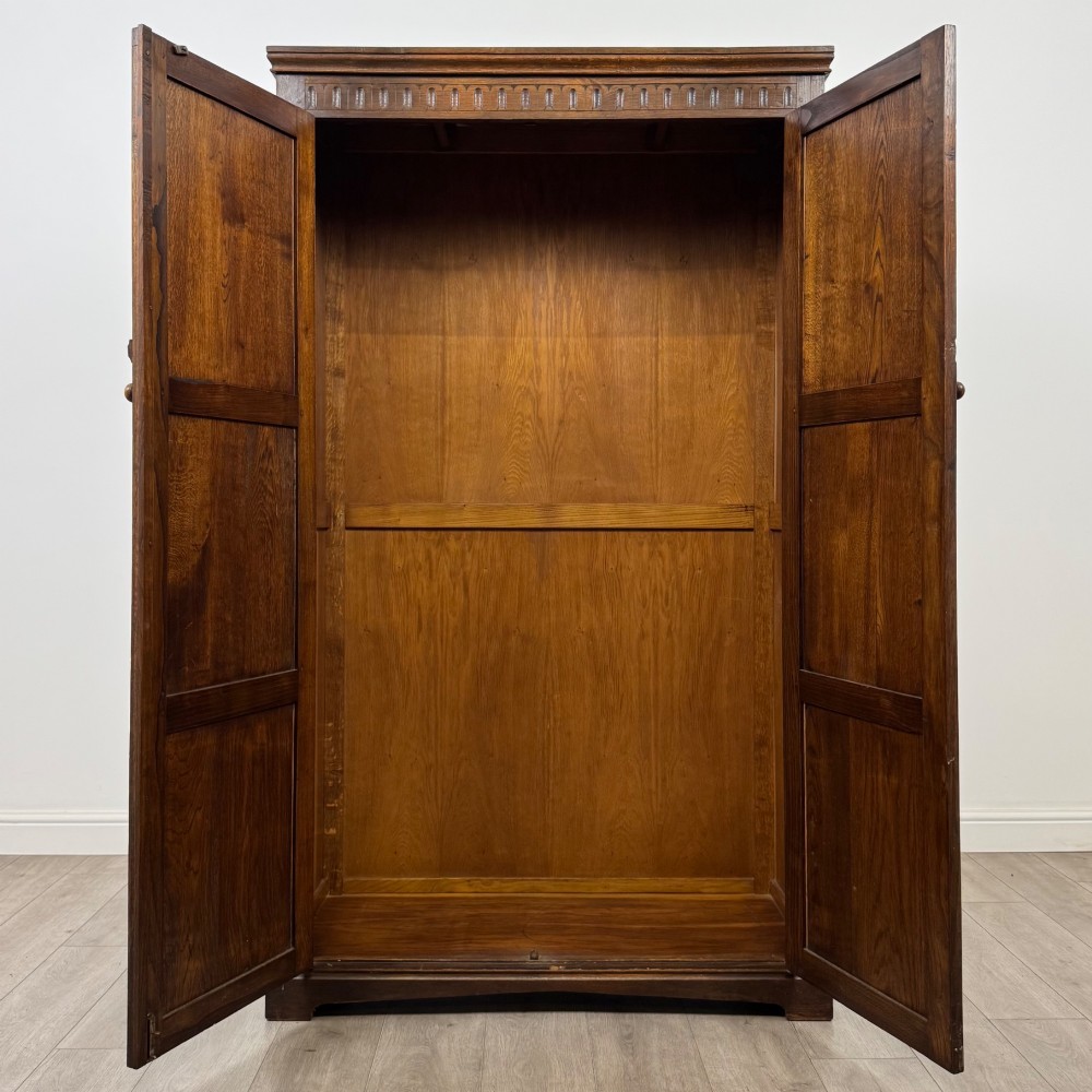 A tall dark oak Edwardian two-door wardrobe featuring carved diamond panel details and decorative iron hinges. View II