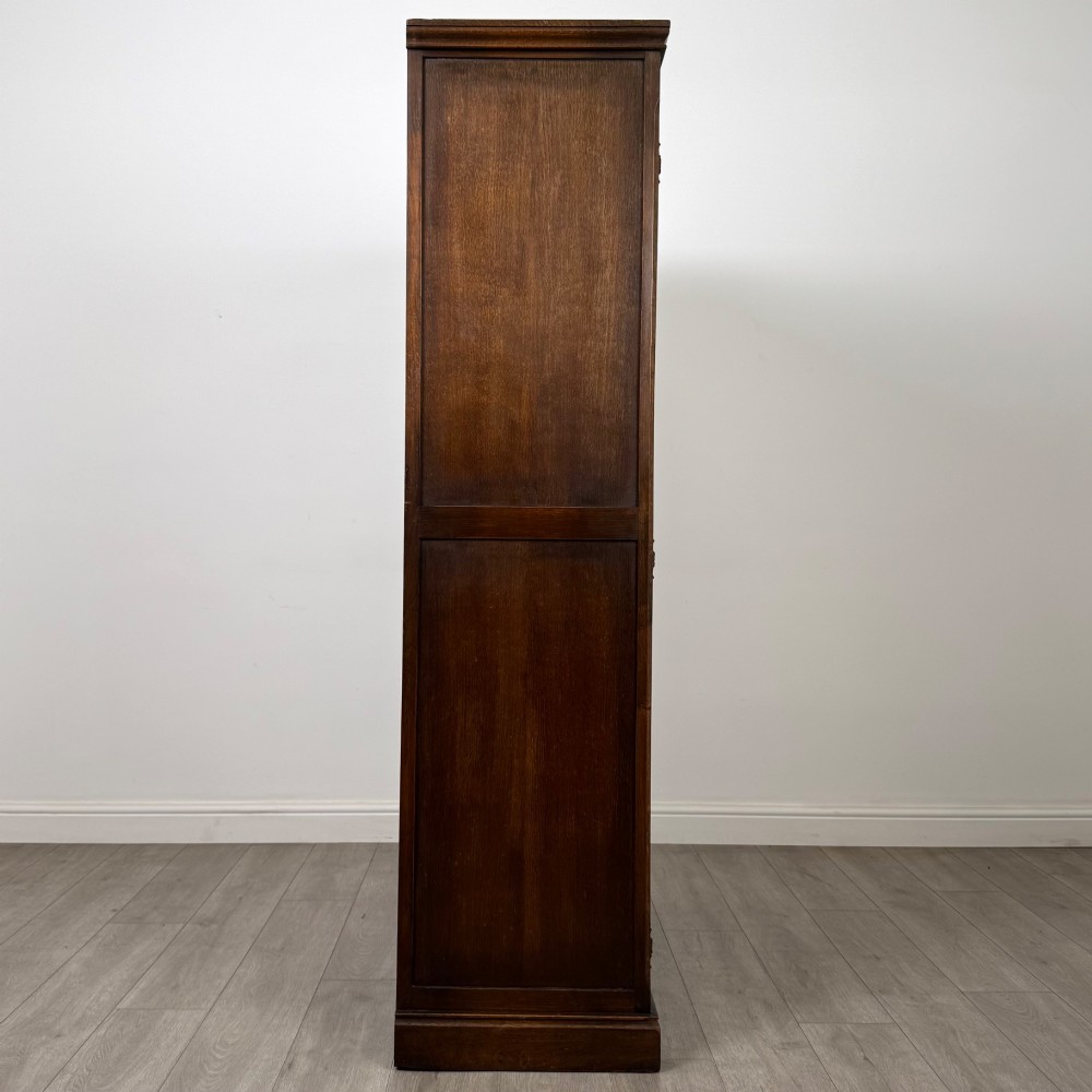 A tall dark oak Edwardian two-door wardrobe featuring carved diamond panel details and decorative iron hinges. View VIII