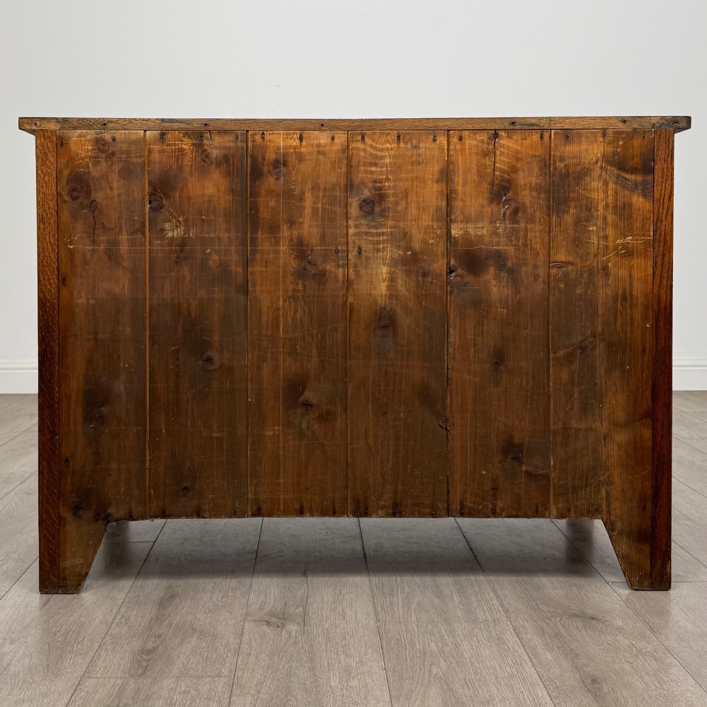 An antique Arts and Crafts oak chest of drawers featuring two short drawers over two full-width drawers with iron drop-ring handles on square backplates. View V