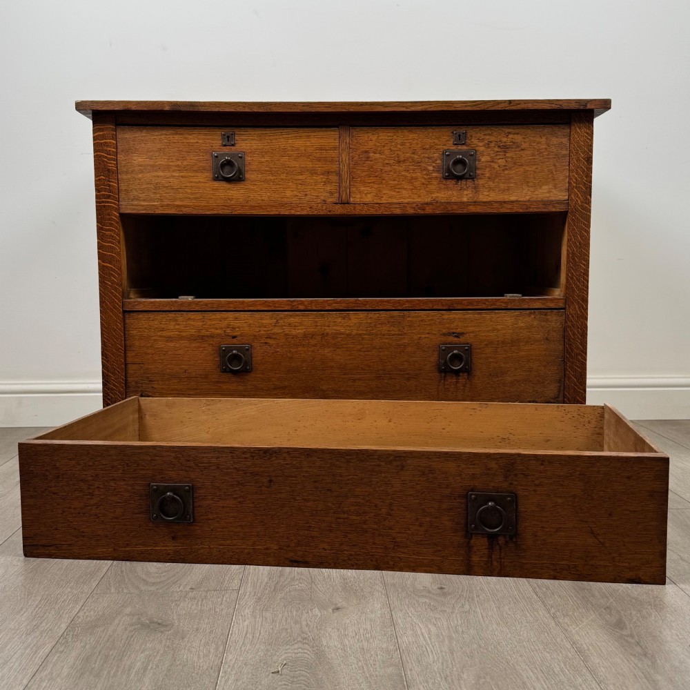 An antique Arts and Crafts oak chest of drawers featuring two short drawers over two full-width drawers with iron drop-ring handles on square backplates. View X