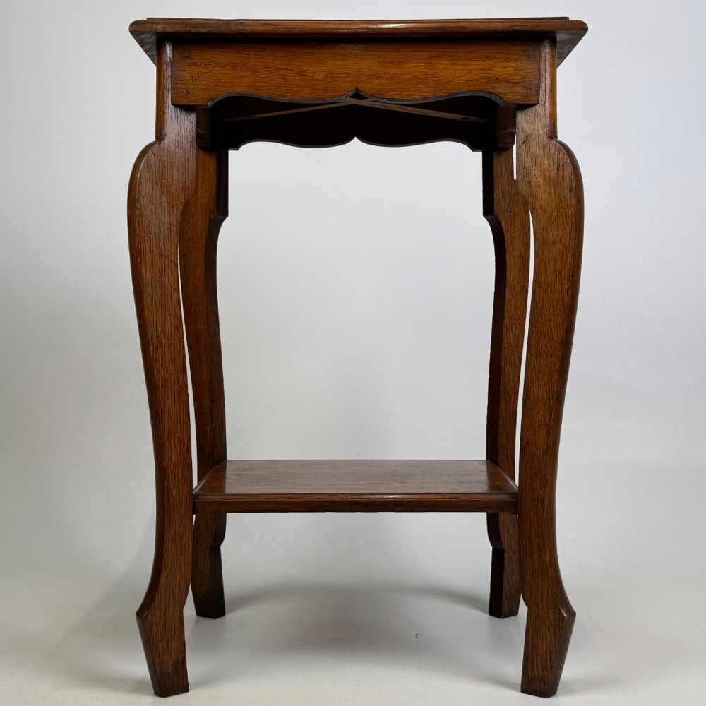 An Edwardian oak side table featuring a rectangular top, shaped apron, flared legs, and a lower square tier.