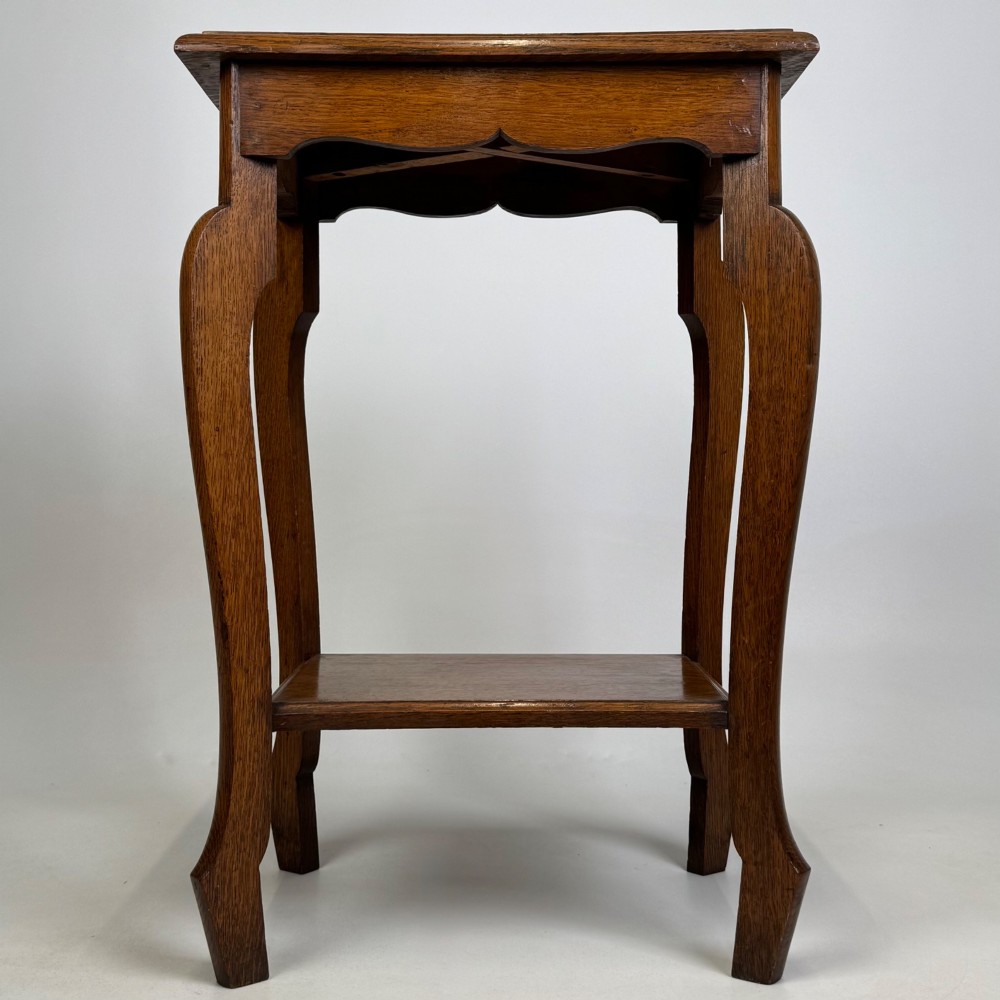 An Edwardian oak side table featuring a rectangular top, shaped apron, flared legs, and a lower square tier. View V