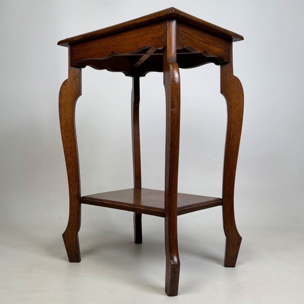 An Edwardian oak side table featuring a rectangular top, shaped apron, flared legs, and a lower square tier. View VI