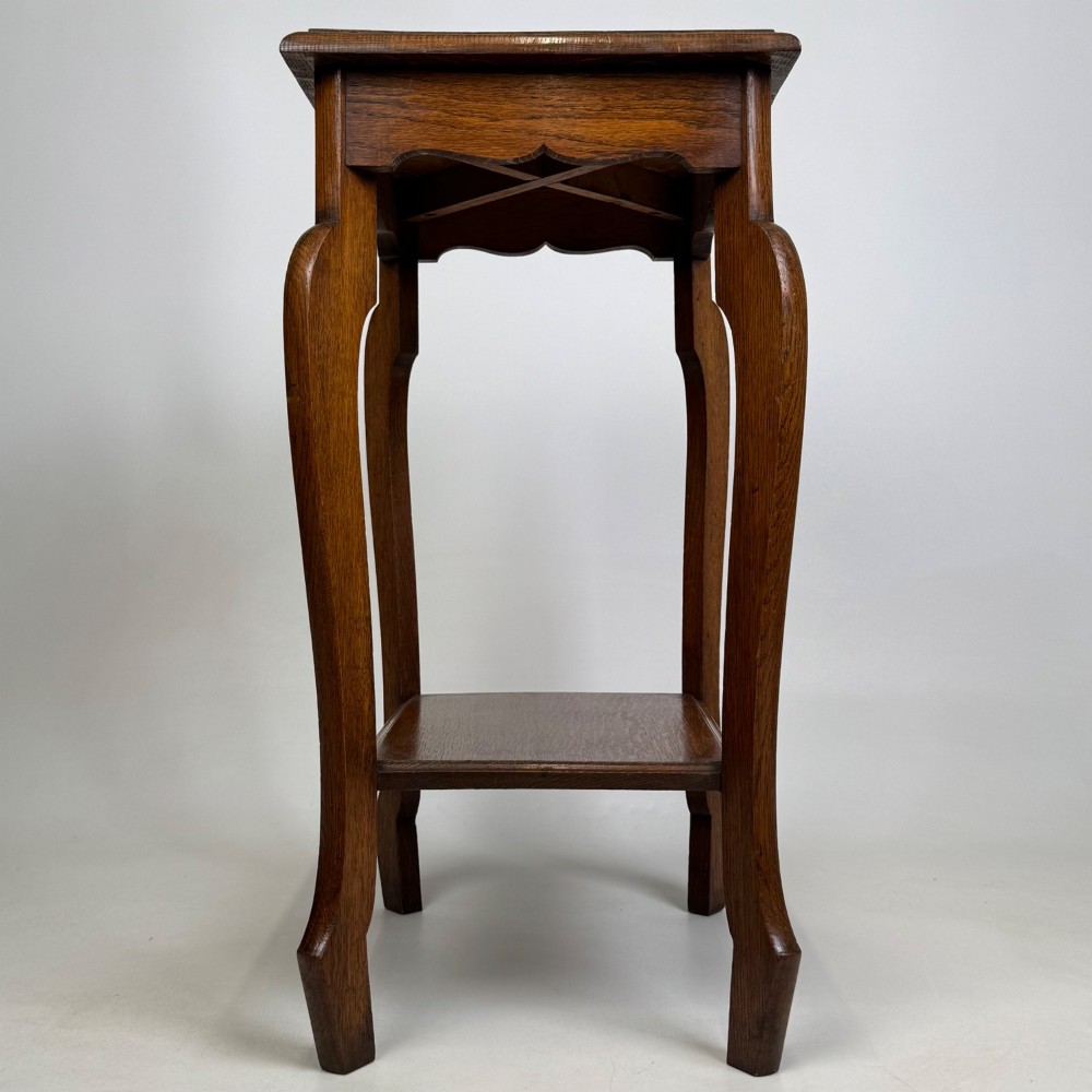 An Edwardian oak side table featuring a rectangular top, shaped apron, flared legs, and a lower square tier. View VII