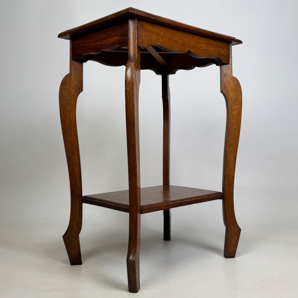 An Edwardian oak side table featuring a rectangular top, shaped apron, flared legs, and a lower square tier. View VIII
