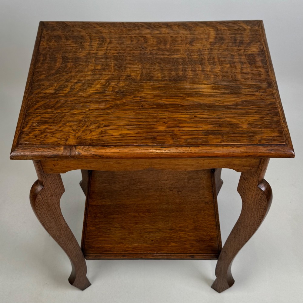 An Edwardian oak side table featuring a rectangular top, shaped apron, flared legs, and a lower square tier. View IX