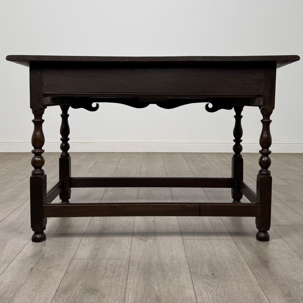 An 18th-century dark oak Georgian side table featuring two frieze drawers with brass handles, turned legs, a shaped apron, and a lower box stretcher. View V