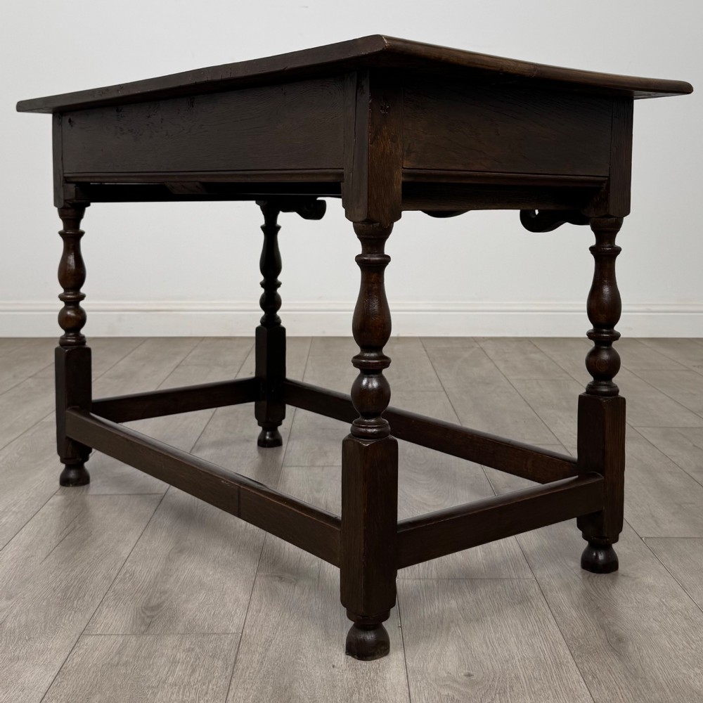 An 18th-century dark oak Georgian side table featuring two frieze drawers with brass handles, turned legs, a shaped apron, and a lower box stretcher. View VI
