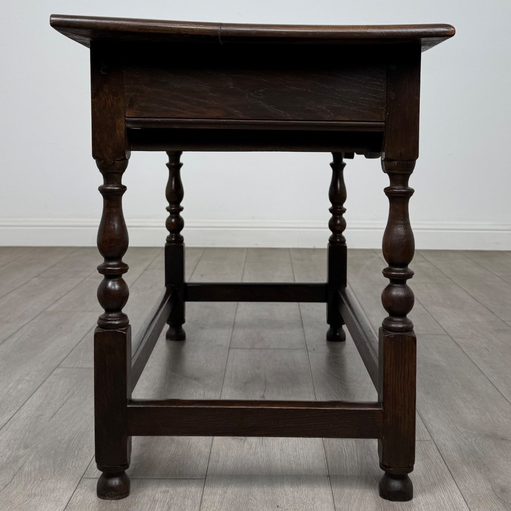 An 18th-century dark oak Georgian side table featuring two frieze drawers with brass handles, turned legs, a shaped apron, and a lower box stretcher. View VII
