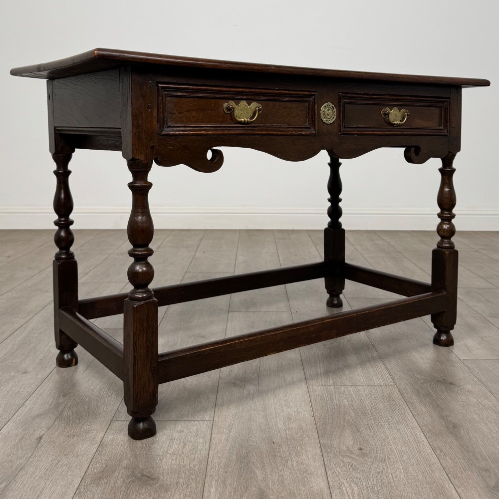 An 18th-century dark oak Georgian side table featuring two frieze drawers with brass handles, turned legs, a shaped apron, and a lower box stretcher. View VIII