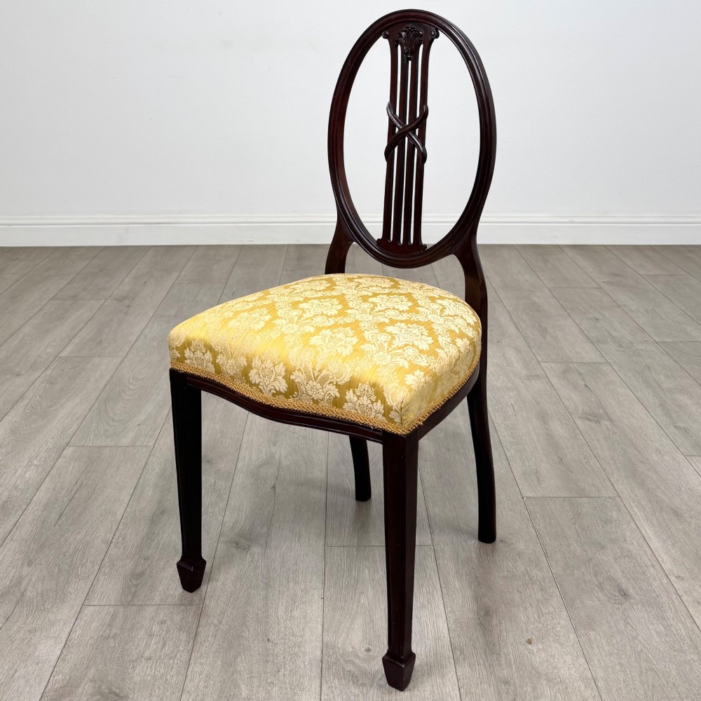 A set of four dark mahogany dining chairs with carved oval backs, slender vertical splats, and gold damask upholstered seats. View II