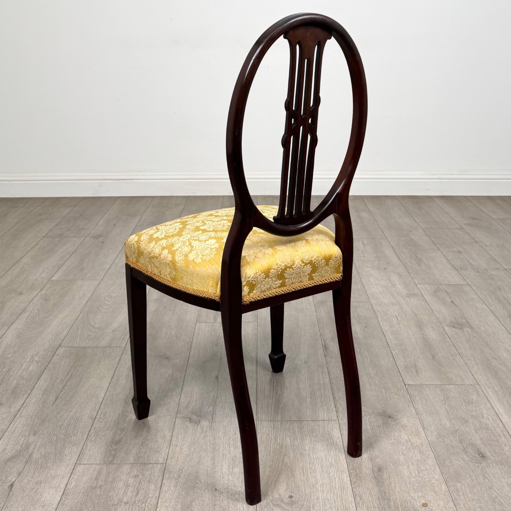 A set of four dark mahogany dining chairs with carved oval backs, slender vertical splats, and gold damask upholstered seats. View III